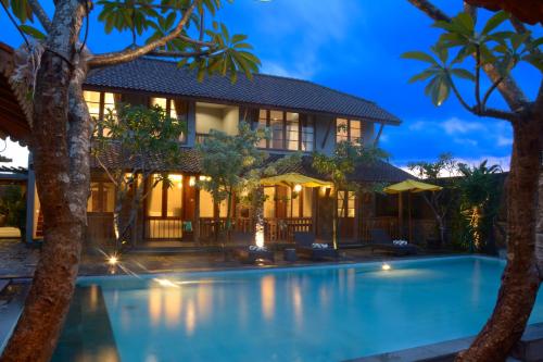a villa with a swimming pool in front of a house at WARISAN Heritage Boutique Hotel in Solo