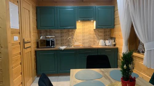 a small kitchen with green cabinets and a table at Domki Szarotki in Groń