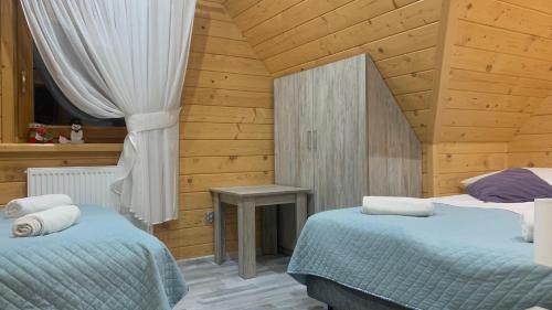 a bedroom with two beds and a wooden ceiling at Domki Szarotki in Groń