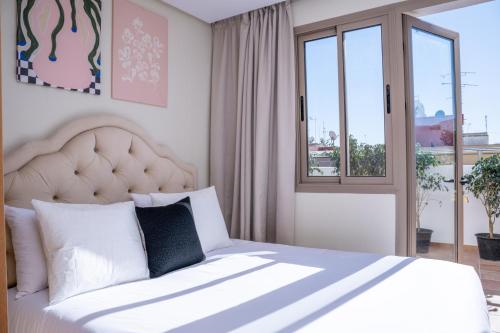 a bedroom with a white bed with a large window at Charming Cozy apartments with terrace, Haut Agdal in Rabat