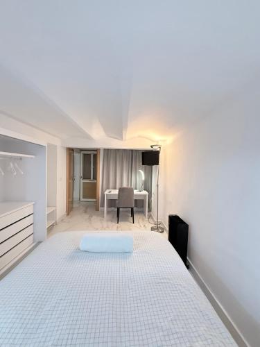 une chambre blanche avec un lit et un bureau dans l'établissement Riad-Entreplanta 2, à Melilla