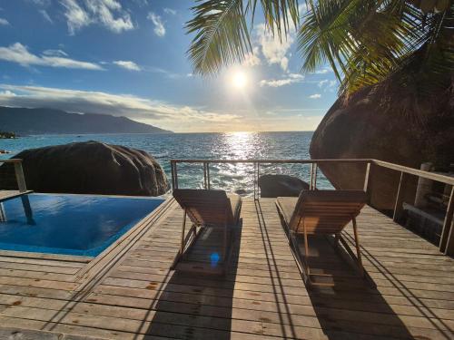 a deck with two chairs and a swimming pool overlooking the ocean at Marquise & Infinity villas in Glacis