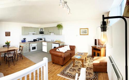 a living room and kitchen with a couch and a table at Number Three The Old Drill Hall in Sturminster Newton