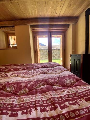 a bed in a room with a large window at Baita Codirosso a Case di Viso in Ponte di Legno