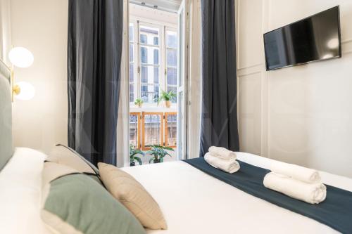 Un dormitorio con una cama blanca y una ventana. en Historic charm steps from top landmarks by REMS, en Málaga