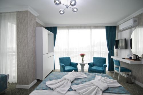 a bedroom with a bed and two blue chairs at Hill Life Hotel in Lüleburgaz