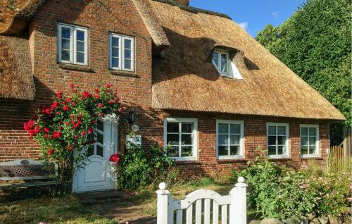 a brick house with a thatched roof with a white fence at Lovely Home In Niebüll Ot Klixbüll in Klixbüll