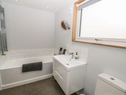 a white bathroom with a tub and a sink at Forest Lodge in Llanfairpwllgwyngyll