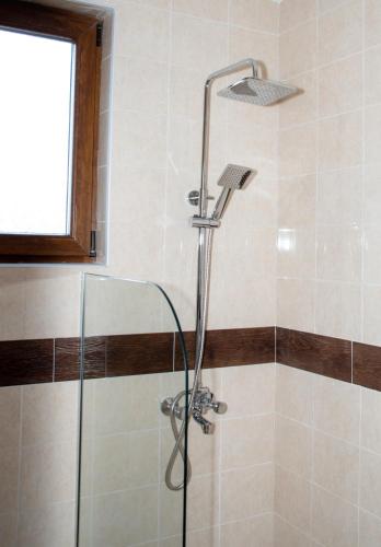a shower with a glass shower head in a bathroom at Орбелус in Bansko