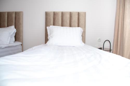 a bed with white sheets and a white pillow at Орбелус in Bansko