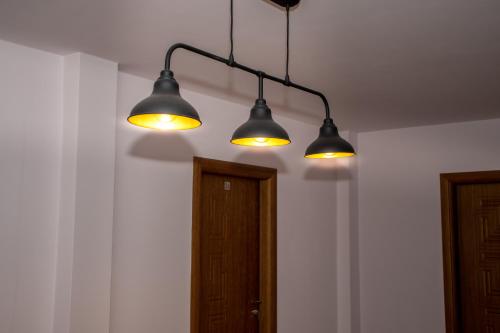 three lights hanging from a ceiling with a door at Орбелус in Bansko