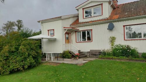 a white house with an umbrella and a yard at Vesteby Hus - a peaceful stay in the countryside! in Grästorp