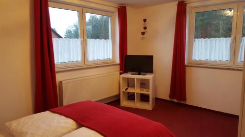 a bedroom with a bed and a tv and windows at Hotel Rosenhof in Isenbüttel