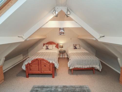 een zolderslaapkamer met twee bedden en een bankje bij Providence Cottage in Whitby