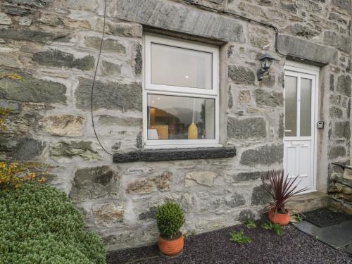 a stone house with a white door and a window at Bryn Tawel in Betws-y-coed