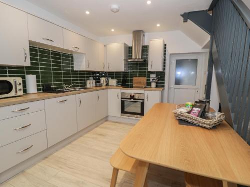 a kitchen with white cabinets and a wooden table at Bryn Tawel in Betws-y-coed