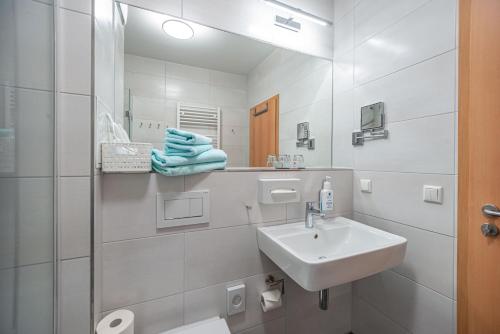 a white bathroom with a sink and a mirror at Am Weststrand Aparthotel Kühlungsborn in Kühlungsborn