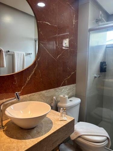 a bathroom with a sink and a toilet and a mirror at Pumma Business Hotel in Canaã dos Carajás