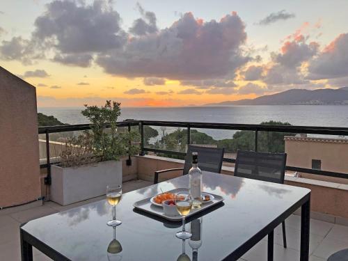 - une table avec deux verres de vin et une assiette de nourriture dans l'établissement So Leil So Fun à Porticcio - 45m2 - Grand lit 180 - Plage à pied - Wifi fibre - Terrasse, à Porticcio