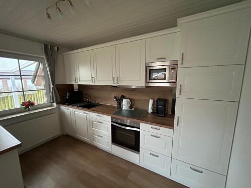 a kitchen with white cabinets and a microwave at Ferienhaus Ankerglück in Friedrichskoog-Spitz