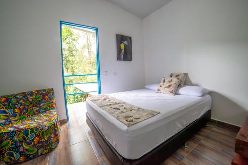 a bedroom with a bed and a chair and a window at La Posada de las Aves in San Rafael