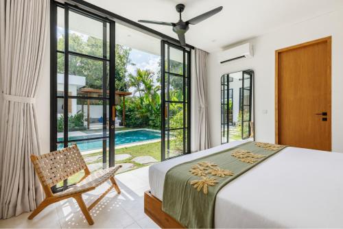 a bedroom with a bed and a chair and a pool at Family Nest Experience Villas in Uluwatu