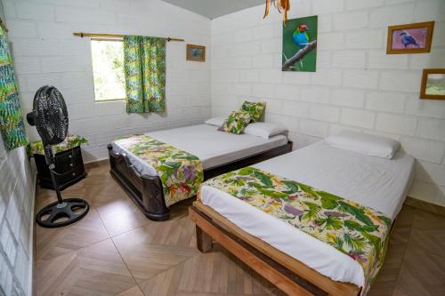 a room with two beds and a fan at La Posada de las Aves in San Rafael