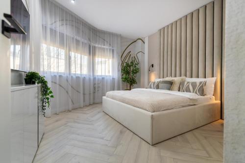 a white bedroom with a large bed and a window at AIASTAY Bucharest River Apartments in Bucharest
