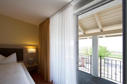 a hotel room with a bed and a balcony at Taste Style Hotel Bären Auggen in Auggen