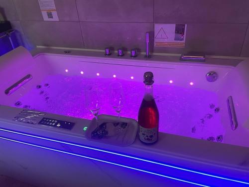 a bath tub with a bottle of wine and wine glasses at Baignoire Balnéo romantic experience - L'époque in Pontarlier