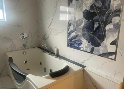 a bathroom with a bath tub and a mirror at Oasis Suits DHA in Lahore