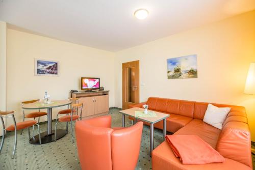 a hotel room with a couch and a tv at Am Weststrand Aparthotel Kühlungsborn in Kühlungsborn