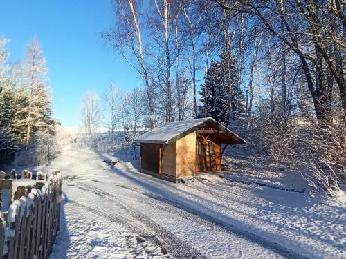 a small wooden cabin in the snow next to a fence at Ferienwohnung am Miriquidi in Marienberg