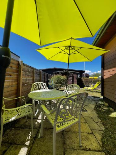 a table and chairs with a yellow umbrella on a patio at Gletterens - Mobile Home proche du lac in Portalban- Dessous