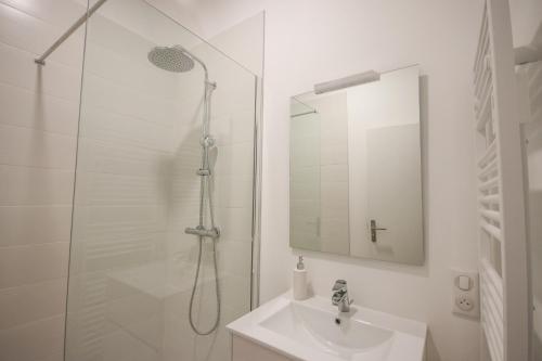Un baño blanco con ducha y lavabo. en Le Pop Art - Parking Privé, en Angulema