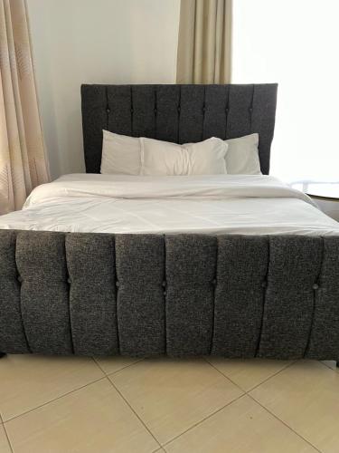 a large bed with a black headboard and white sheets at Snowhaven One bedroom accomodation Kitengela in Kitengela 