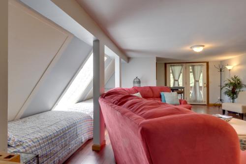 a living room with a red couch in a attic at 3 Mi to Great Smoky Mtn NP Riverfront Retreat in Townsend