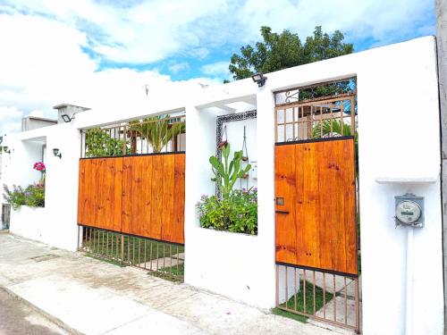 a white house with wooden doors and plants at Casa Las Palmas, comfort and privacy in Mahahual