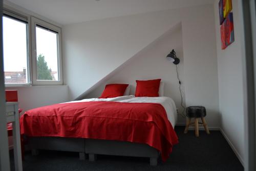 a white bedroom with a red bed with red pillows at Guesthouse de Hoogkamp in Arnhem