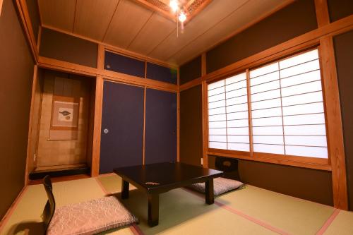 a room with a table and a bench in a room at 鵜原館 -Ubarakan- in Katsuura