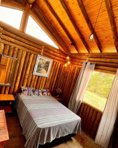 a bedroom with a bed in a wooden room at Chalés do Caminho - Aconchego in Santa Rita do Rio Abaixo