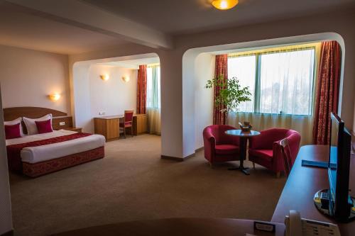 a hotel room with a bed and a table and chairs at Hotel Sevlievo Plaza in Sevlievo