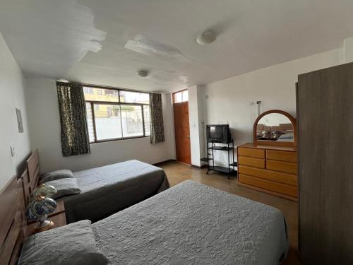 1 dormitorio con 2 camas, tocador y espejo en Casa Extremadura, en Lima