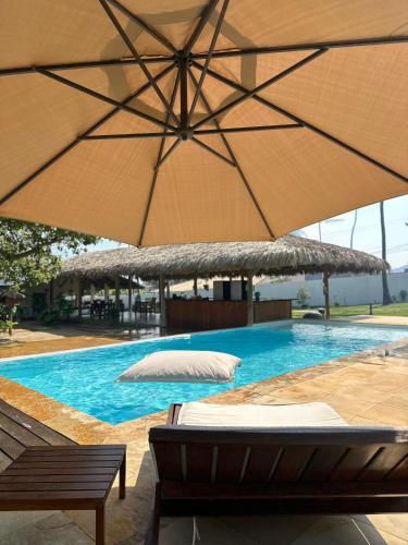 a swimming pool with two umbrellas and a swimming pool at Pousada Casa Caju Bangalows in Cumbuco
