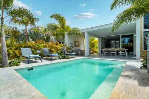 a swimming pool in front of a house with palm trees at Delfins Residences in Kralendijk