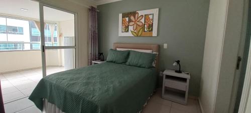 a bedroom with a green bed and a window at Ótima Localização!!! Apartamento De Frente No Centro De Capão Da Canoa in Capão da Canoa