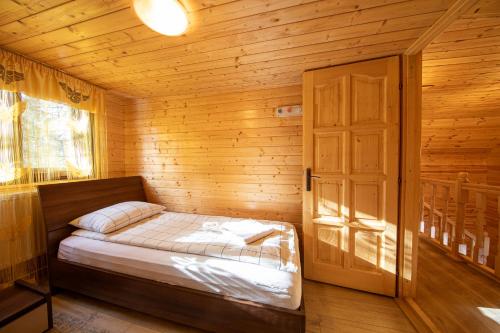 a small room with a bed in a wooden cabin at Cabana Adrienne in Izvoru Mureşului