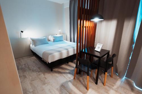 a bedroom with a bed and a table with a chair at RentUp Suites Salta in Salta