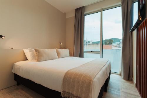 a bedroom with a large bed and a large window at RentUp Suites Salta in Salta
