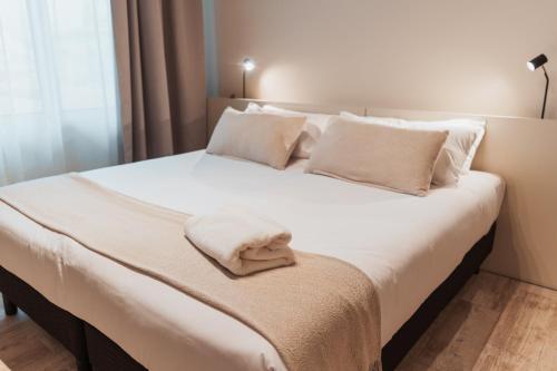 a white bed with white pillows and a towel on it at RentUp Suites Salta in Salta